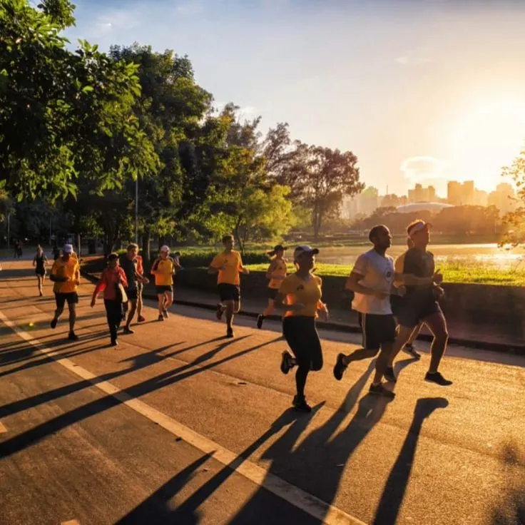 Group walking along a lakeside path at sunrise